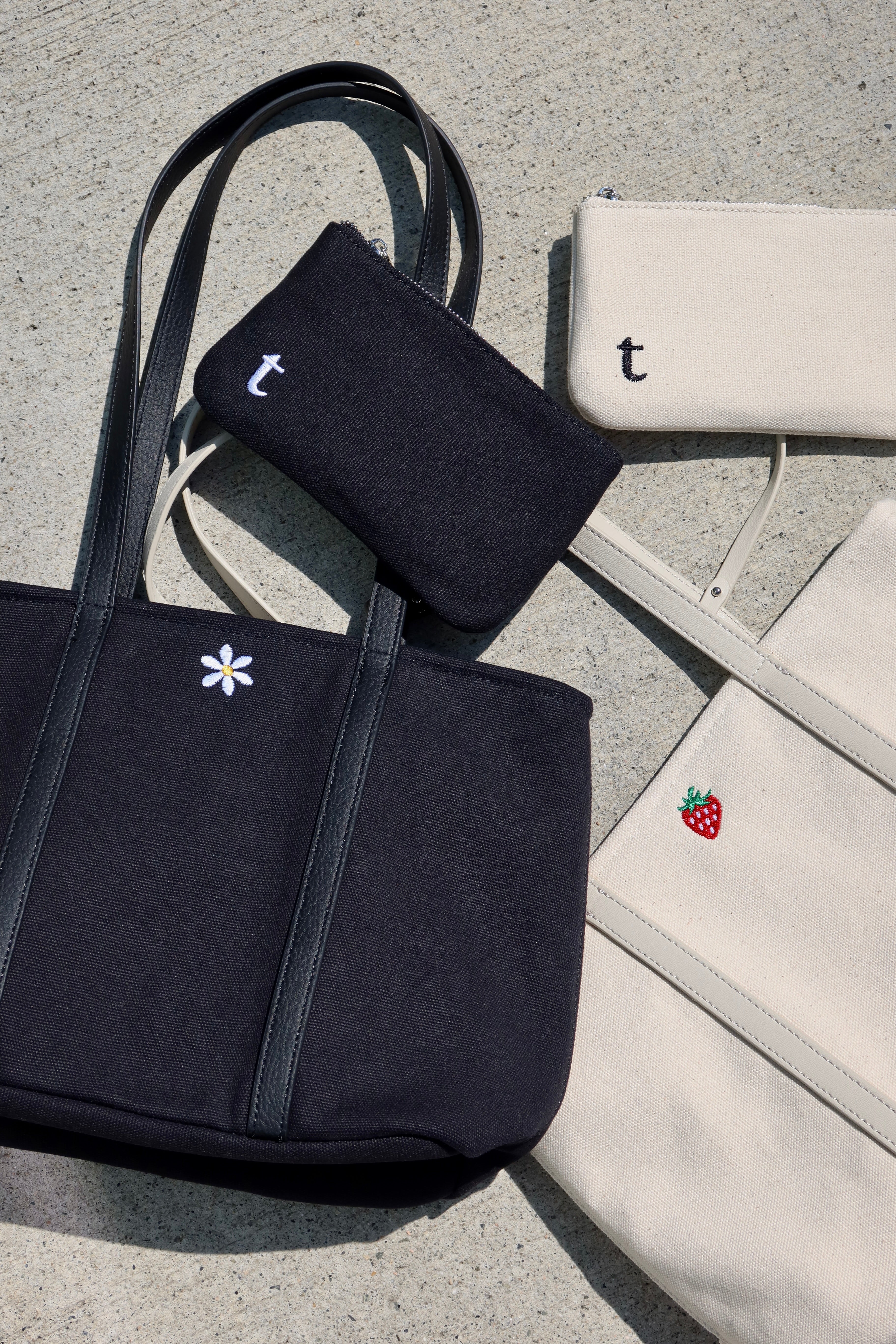 A black tote bag with flower embroidery and a white tote bag with a strawberry embroidery. minimalist canvas made tote bags for everyday use
