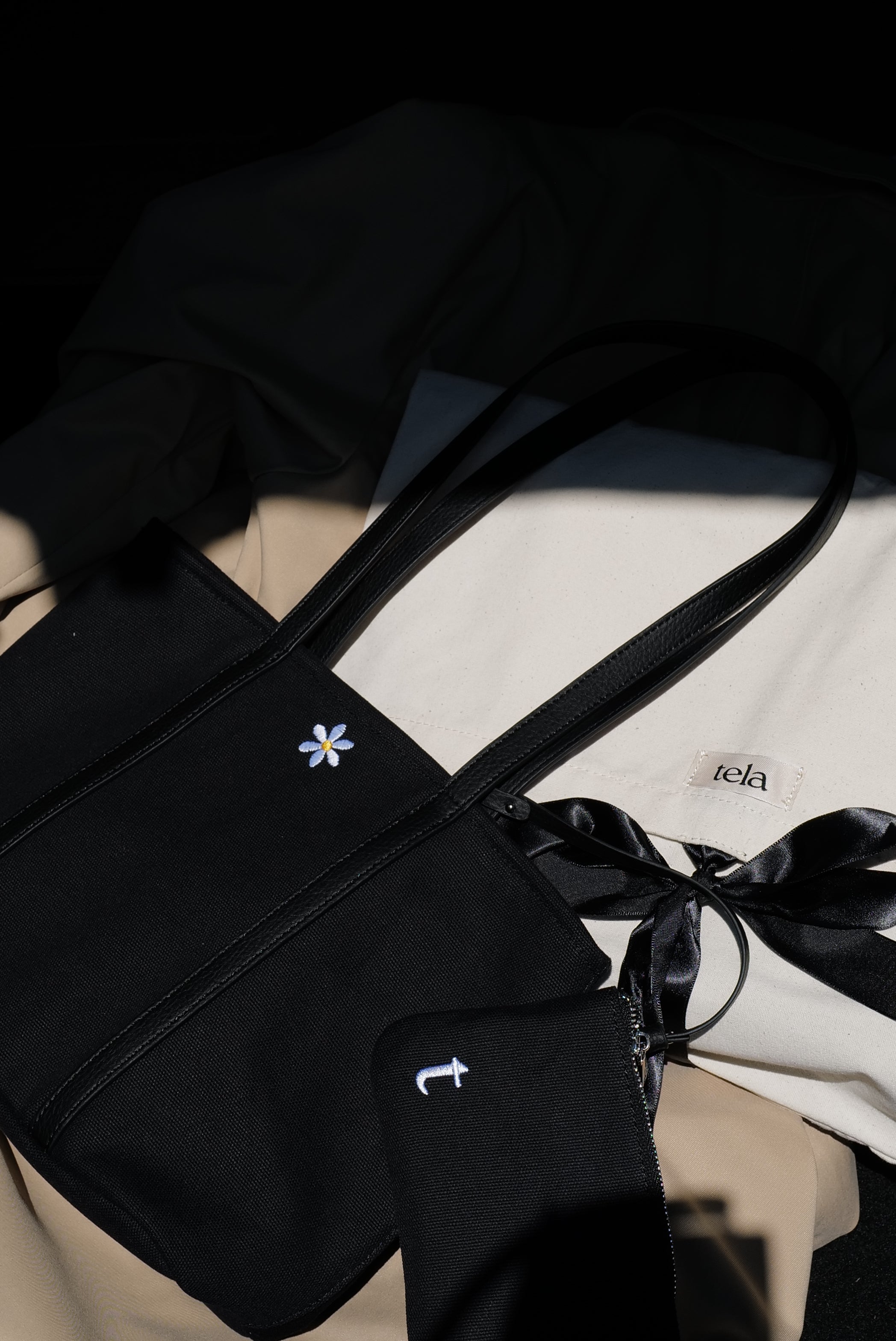 a minimalist black tote bag and removable pouch on top of dust bag.